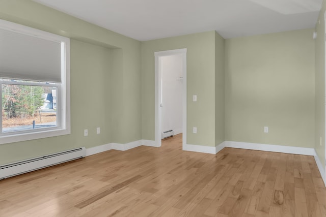 unfurnished room featuring baseboard heating and light wood-type flooring