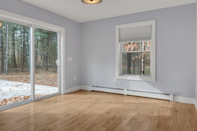 unfurnished room with baseboard heating and light hardwood / wood-style flooring