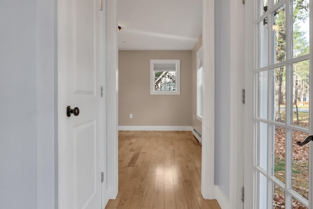 hallway with a baseboard heating unit and light wood-type flooring