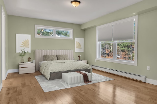 bedroom featuring baseboard heating and light hardwood / wood-style flooring