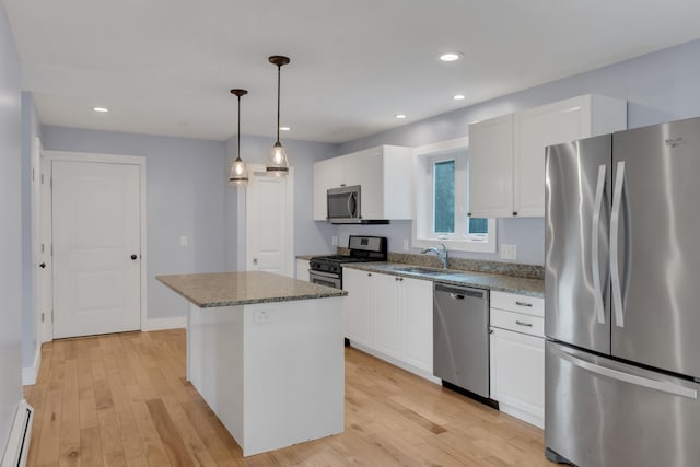 kitchen featuring white cabinets, light hardwood / wood-style flooring, a kitchen island, pendant lighting, and appliances with stainless steel finishes