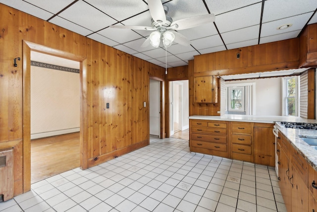 kitchen with wooden walls, light tile patterned floors, ceiling fan, and a baseboard radiator