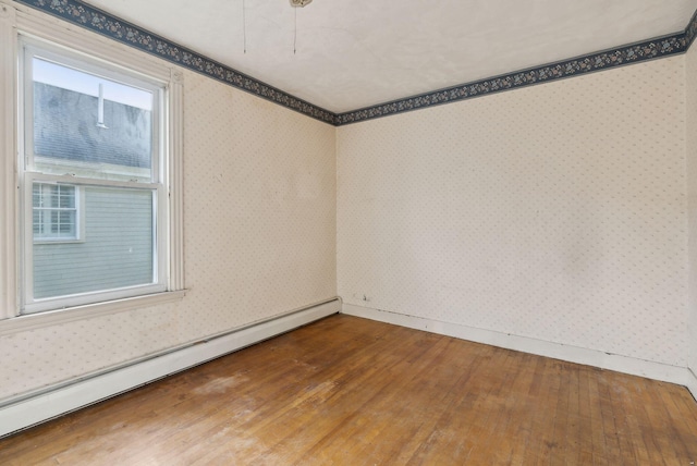 spare room with baseboard heating and wood-type flooring