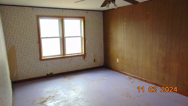 unfurnished room with wooden walls and ceiling fan