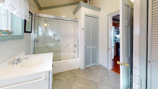 bathroom featuring vanity, combined bath / shower with glass door, tile walls, and ornamental molding