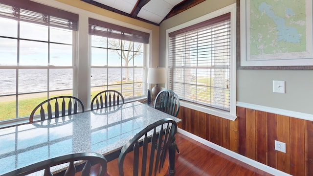 dining room with a water view, a healthy amount of sunlight, vaulted ceiling, and wood-type flooring