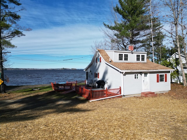 rear view of house with a yard and a deck with water view