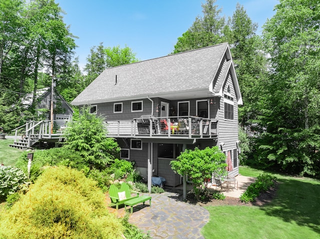 rear view of house featuring a deck, a yard, and a patio area