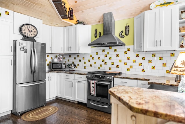 kitchen featuring stainless steel appliances, dark stone countertops, white cabinetry, and exhaust hood