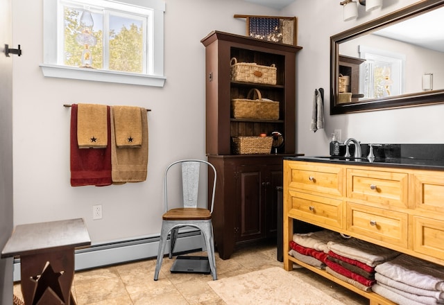 interior space with a baseboard heating unit, vanity, and a healthy amount of sunlight