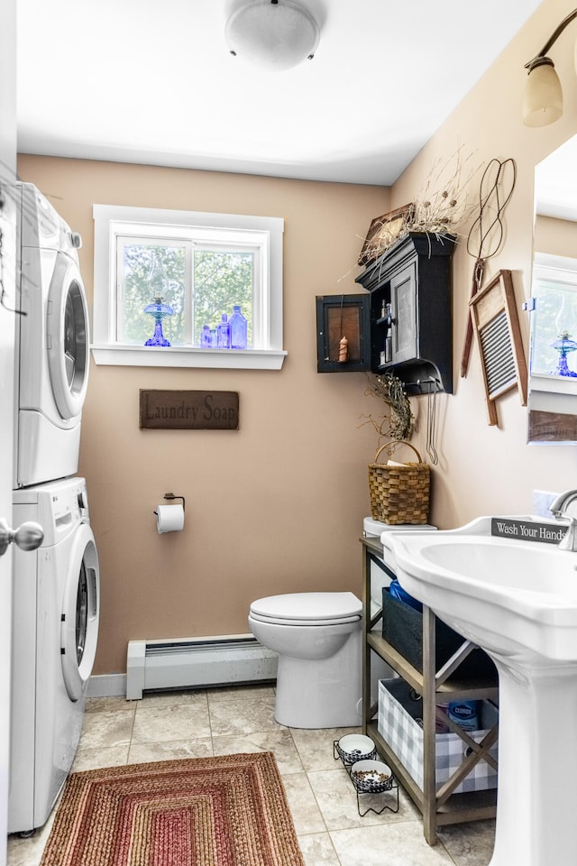 bathroom with tile patterned floors, stacked washer and dryer, sink, a baseboard radiator, and toilet