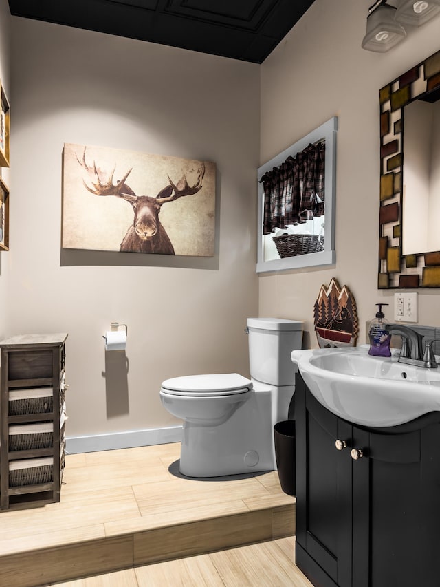 bathroom with hardwood / wood-style flooring, vanity, and toilet