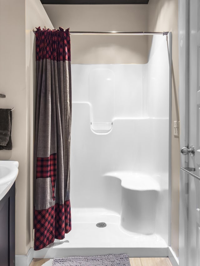 bathroom with walk in shower, hardwood / wood-style floors, and vanity