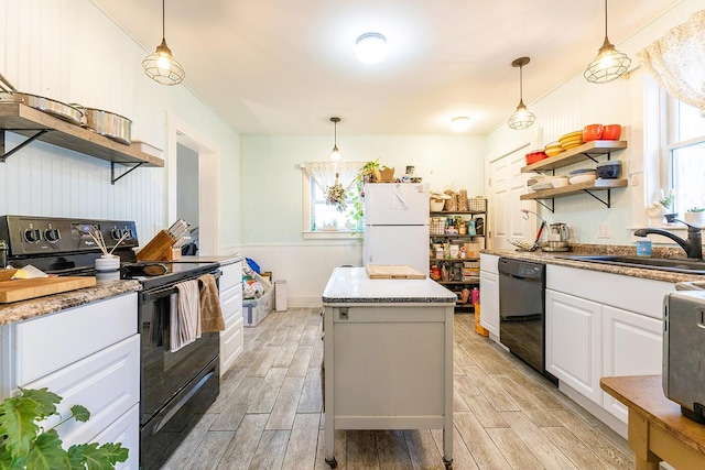 kitchen featuring a healthy amount of sunlight, a center island, white cabinets, and black appliances