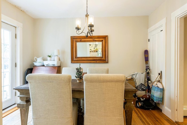 dining space featuring wood-type flooring, plenty of natural light, and a notable chandelier