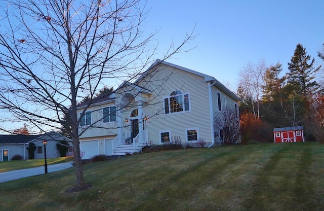 raised ranch featuring a storage unit, a garage, and a front lawn