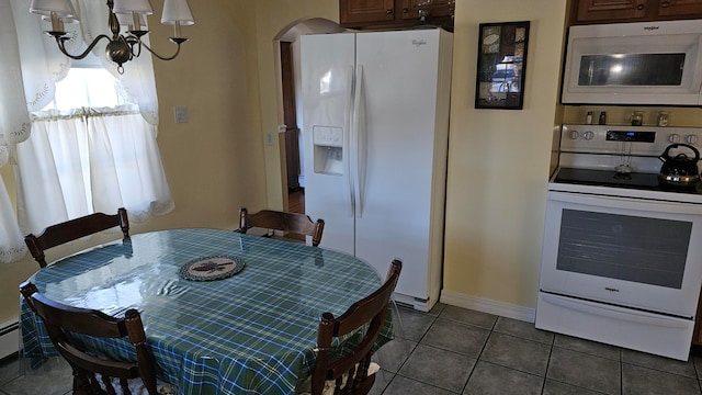 dining area with baseboard heating, a notable chandelier, and dark tile patterned flooring