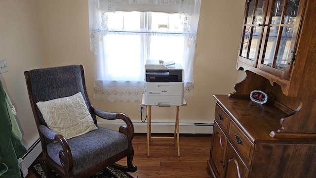 sitting room featuring a wealth of natural light, a baseboard heating unit, and dark hardwood / wood-style flooring