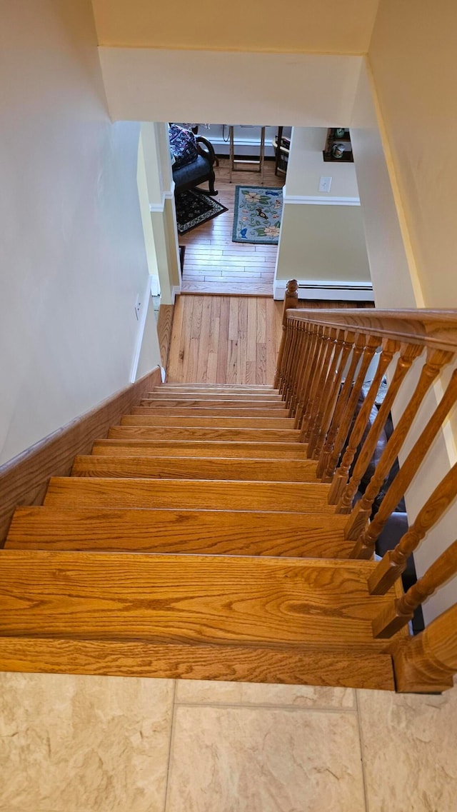 stairway featuring baseboard heating and hardwood / wood-style flooring