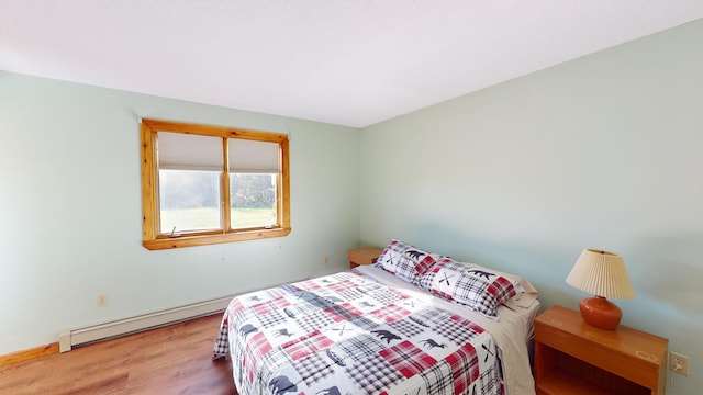 bedroom featuring hardwood / wood-style floors and a baseboard heating unit