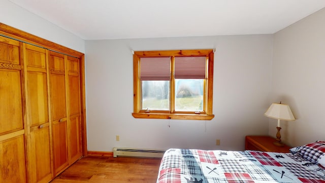 bedroom featuring light hardwood / wood-style floors, a baseboard radiator, and a closet