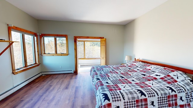 unfurnished bedroom with hardwood / wood-style floors, multiple windows, and a baseboard heating unit