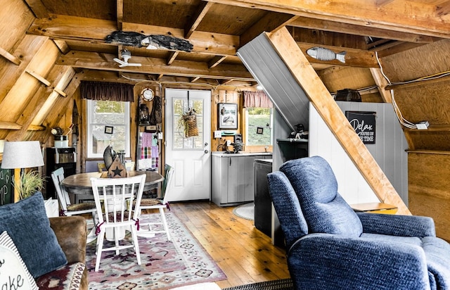 dining room with lofted ceiling with beams, hardwood / wood-style flooring, and wood walls