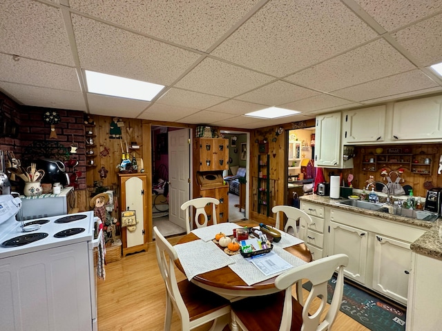 kitchen featuring a drop ceiling, wood walls, sink, electric range, and light wood-type flooring