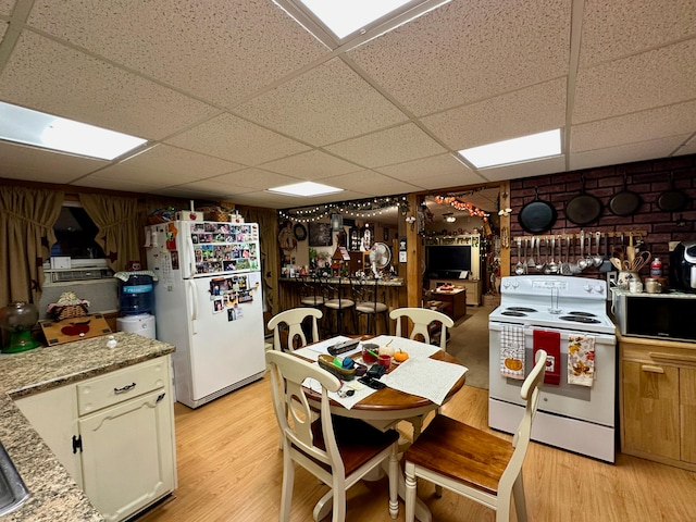 kitchen featuring a drop ceiling, wood walls, light stone countertops, light wood-type flooring, and white appliances