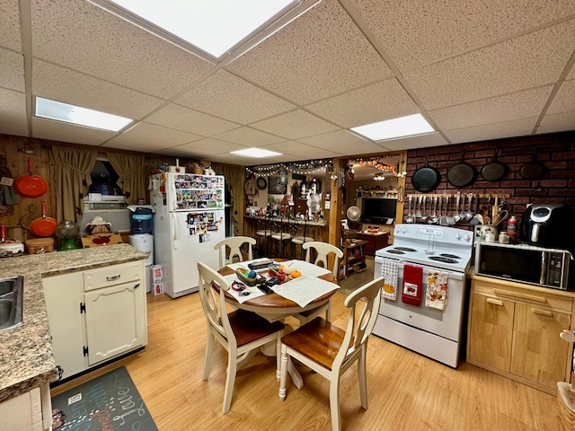 kitchen with a paneled ceiling, white appliances, and light hardwood / wood-style flooring