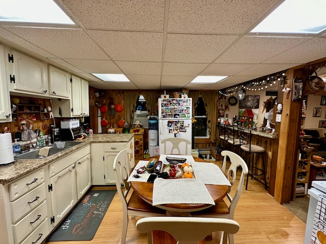 kitchen with wood walls, light hardwood / wood-style flooring, a paneled ceiling, and sink