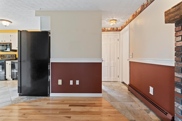 kitchen featuring black appliances, white cabinetry, a textured ceiling, and a baseboard heating unit