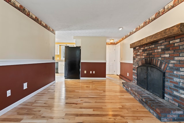 unfurnished living room featuring a fireplace, baseboard heating, and light hardwood / wood-style flooring