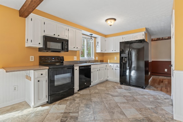 kitchen featuring white cabinetry, sink, black appliances, and kitchen peninsula