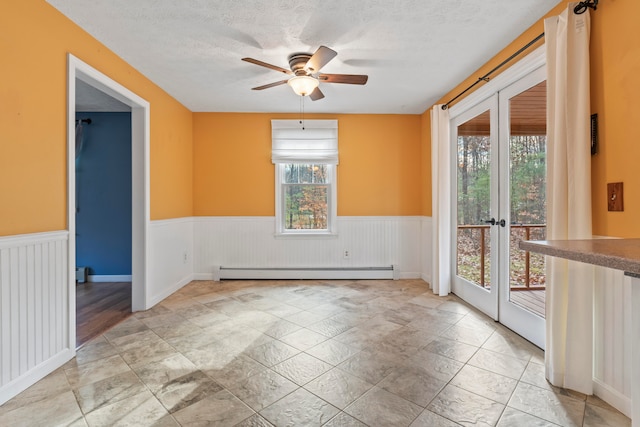 empty room featuring ceiling fan, french doors, a textured ceiling, and a baseboard heating unit