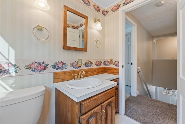 bathroom featuring toilet, vanity, a textured ceiling, and tile patterned floors