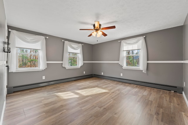 spare room featuring ceiling fan, plenty of natural light, light hardwood / wood-style flooring, and baseboard heating