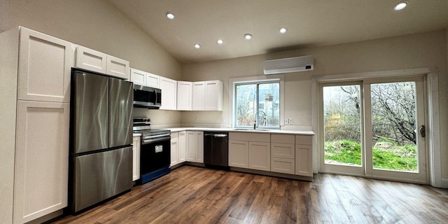 kitchen with appliances with stainless steel finishes, a wall mounted air conditioner, a sink, vaulted ceiling, and recessed lighting