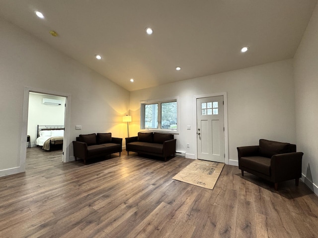 living room with a wall unit AC, wood finished floors, recessed lighting, lofted ceiling, and baseboards
