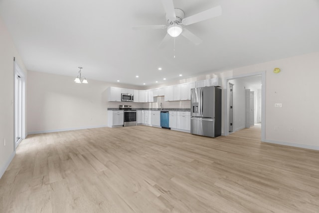 kitchen featuring stainless steel appliances, white cabinetry, ceiling fan with notable chandelier, light wood-type flooring, and pendant lighting