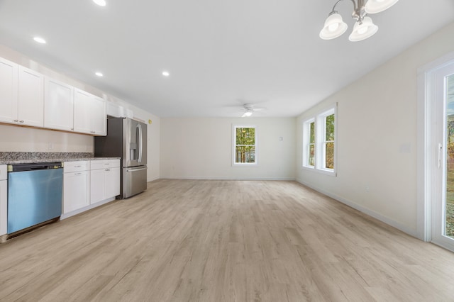 kitchen with white cabinetry, light hardwood / wood-style flooring, appliances with stainless steel finishes, and decorative light fixtures