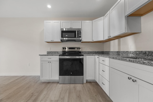 kitchen featuring light hardwood / wood-style flooring, white cabinetry, light stone countertops, and stainless steel appliances