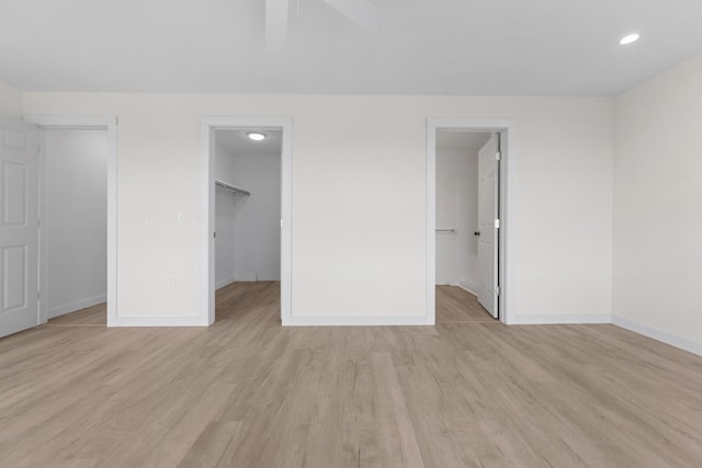 unfurnished bedroom with light hardwood / wood-style floors, a closet, a spacious closet, and ensuite bathroom