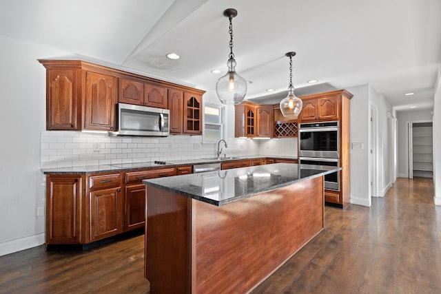 kitchen featuring appliances with stainless steel finishes, a center island, dark hardwood / wood-style floors, and dark stone countertops