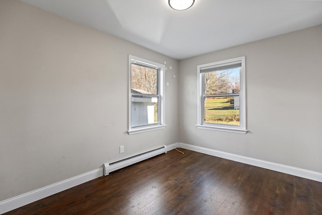 spare room featuring dark wood-type flooring and a baseboard heating unit