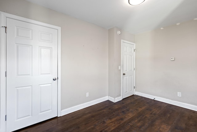 unfurnished room with dark wood-type flooring