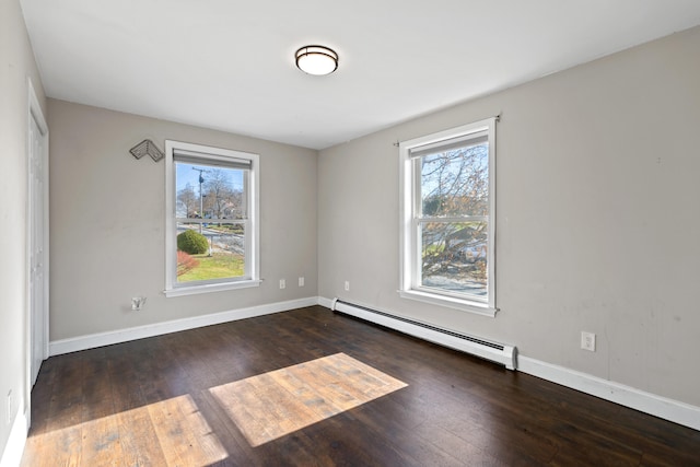 empty room with dark hardwood / wood-style flooring, a baseboard radiator, and a healthy amount of sunlight