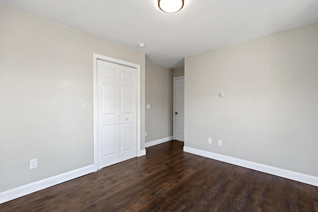 unfurnished bedroom with dark wood-type flooring and a closet