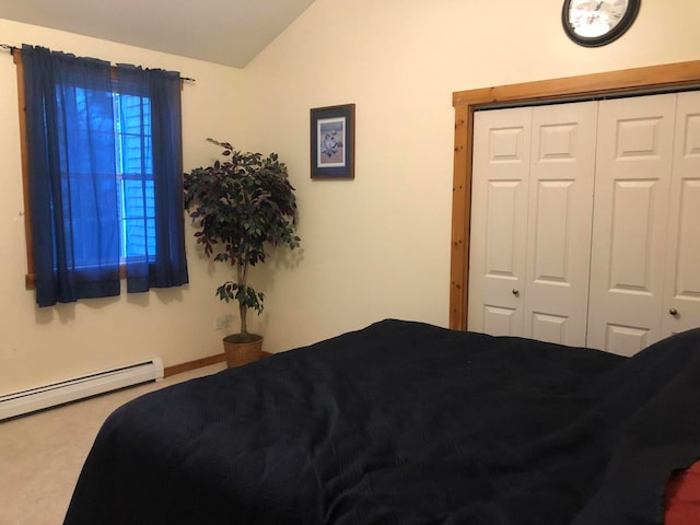 carpeted bedroom with a closet, vaulted ceiling, and a baseboard heating unit