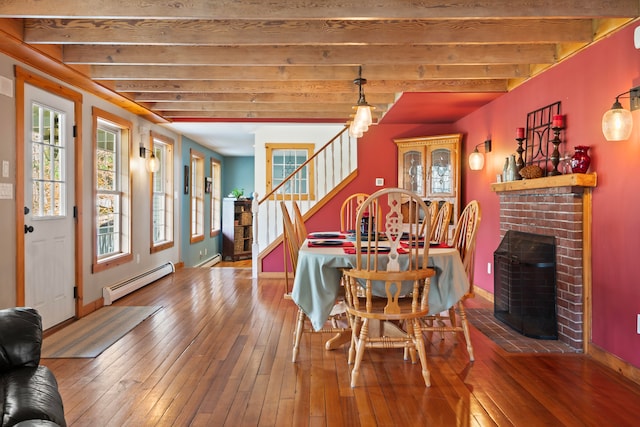 dining area with beamed ceiling, wood-type flooring, a fireplace, and a baseboard heating unit